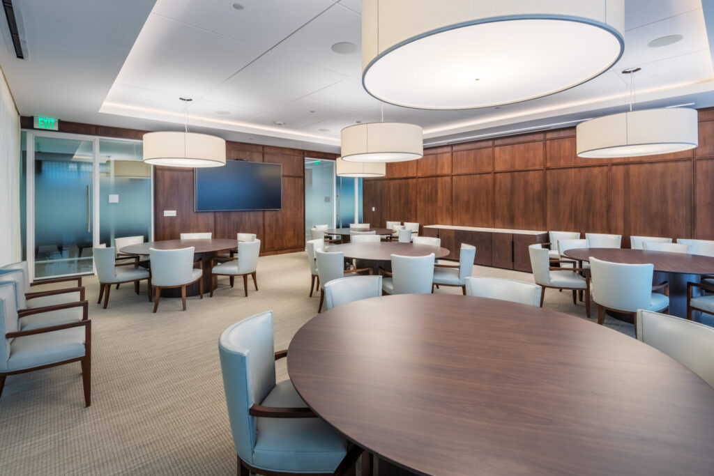 Glenlake Seven Martin Marietta Headquarters Meeting Room with Round Tables, Wood Panels, Round Light Fixtures, and a Mounted Screen